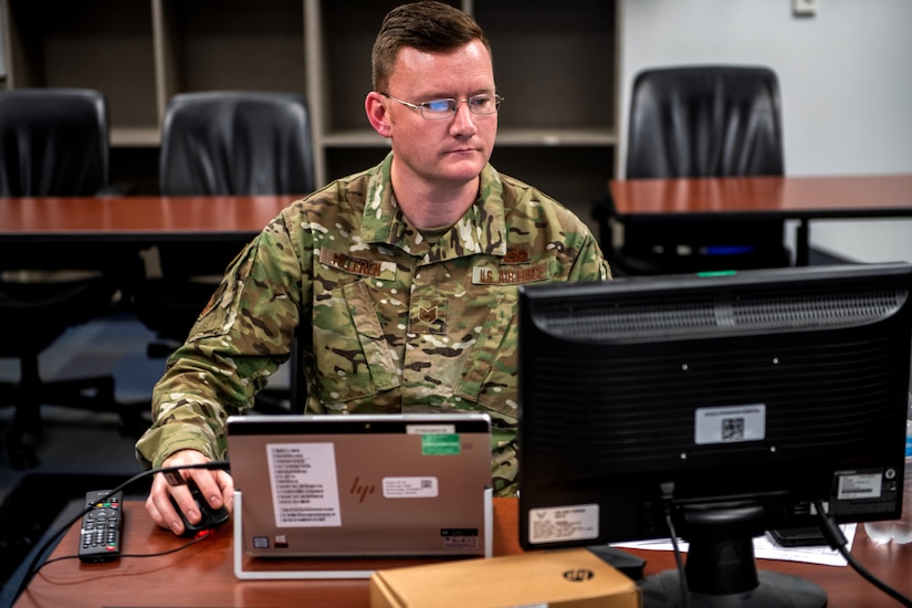 An airman works on a computer.