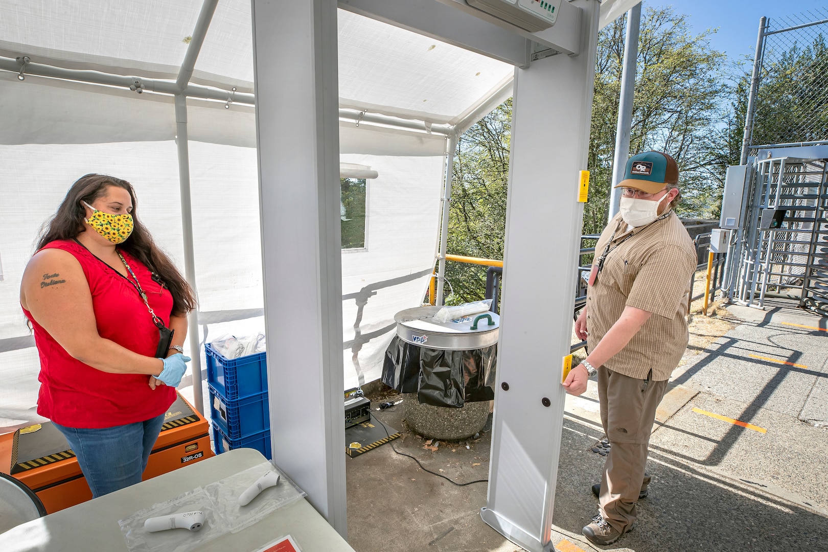 Julie Holter, left, Code 308 facility manager representative, assists Trevor Cox, right, Code 2340 nuclear chief test engineer, while he checks his temperature using a newly-installed SafeCheck infrared body temperature detector Aug. 25, 2020 inside the Decatur Gate at Puget Sound Naval Shipyard & Intermediate Maintenance Facility in Bremerton, Washington.