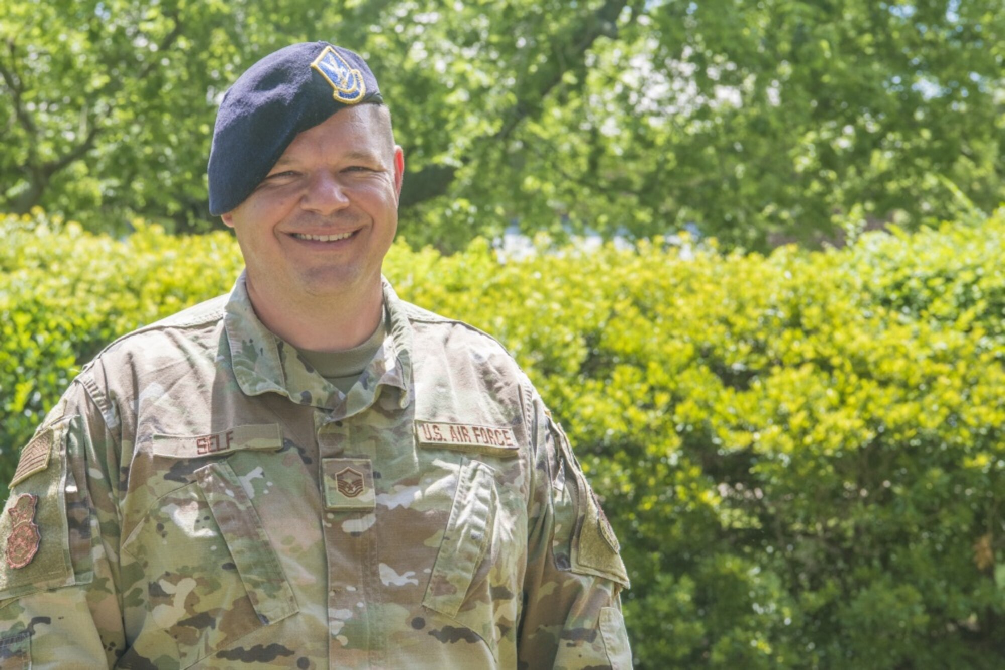 A security forces airman wearing a beret smiles at the camera