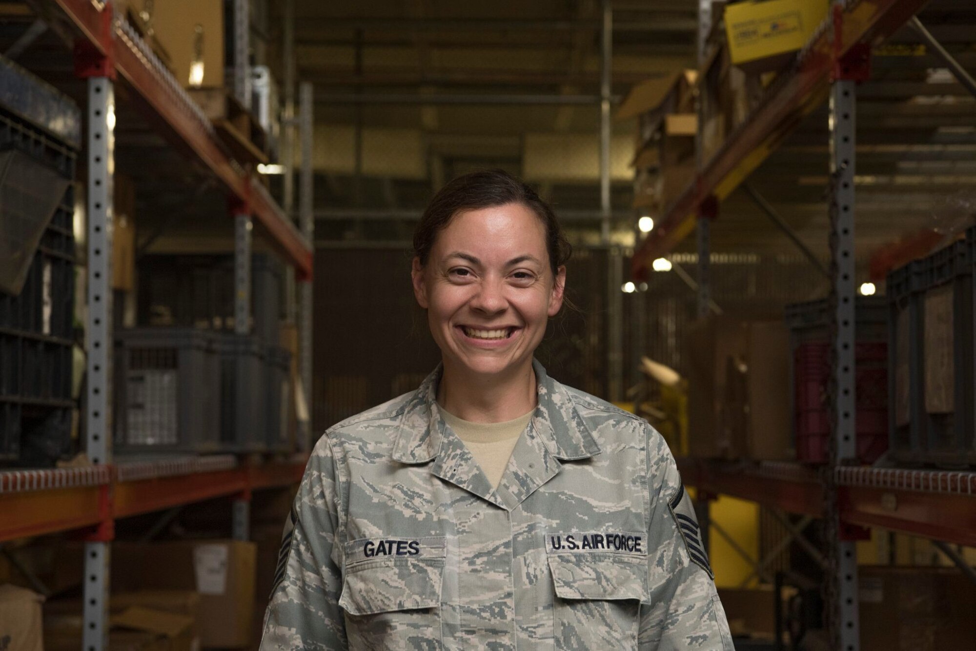 An Airman standing in the middle of two shelves in a warehouse