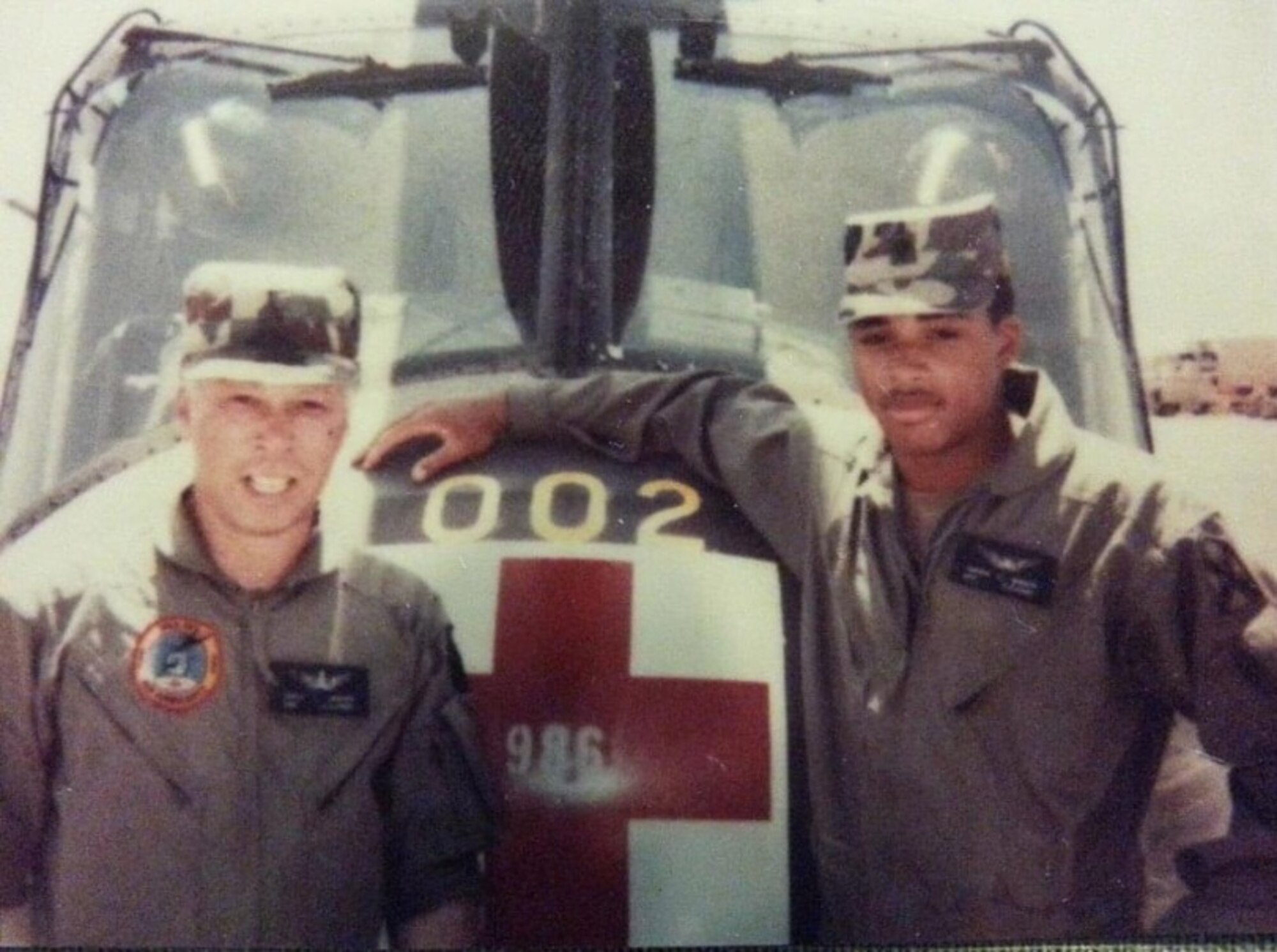 Two men are lean on the front of a medical helicopter