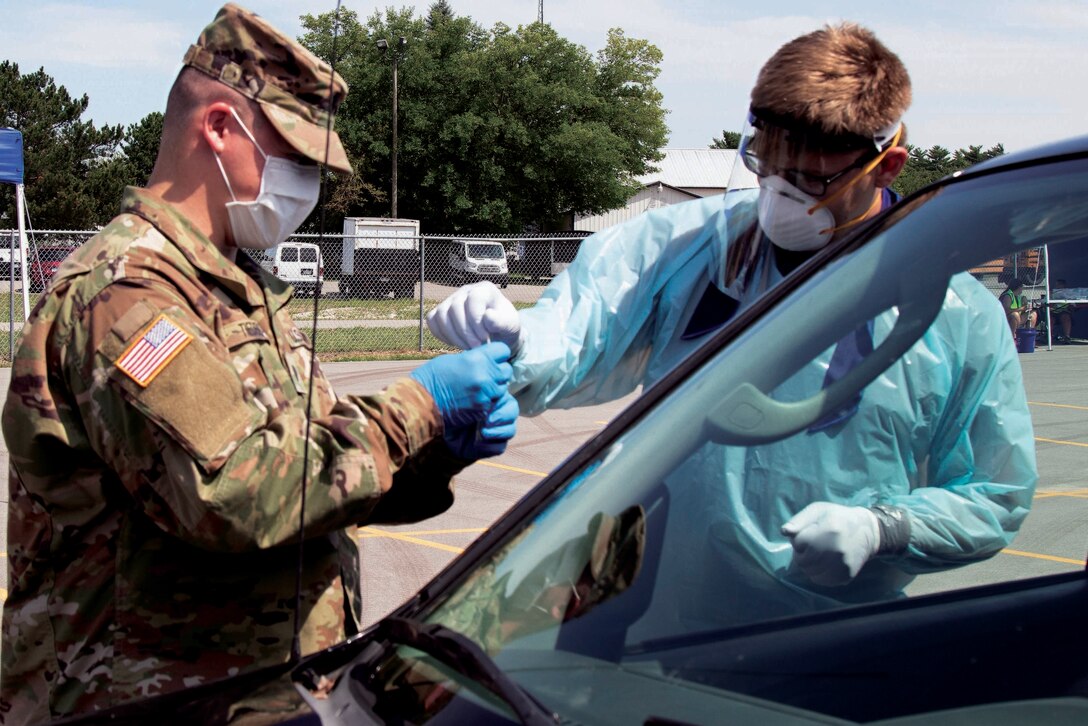 Soldiers wearing masks and personal protective equipment conduct drive-thru COVID-19 tests.