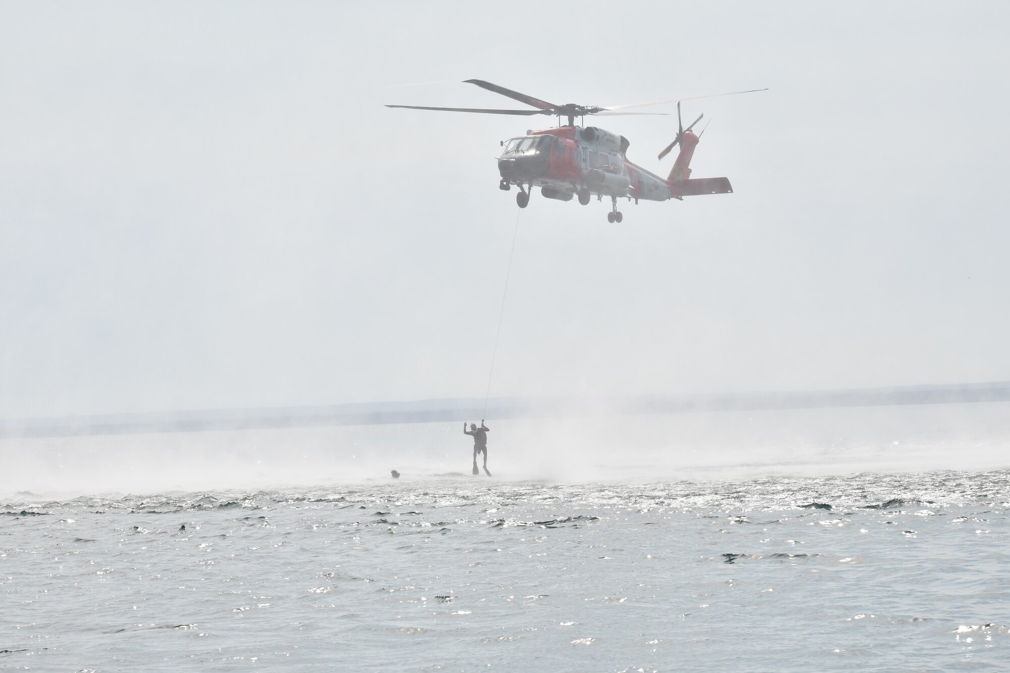 A U.S. Coast Guard MH-60 Jayhawk from Air Station Traverse City, Michigan hoists an F-16 pilot from the 148th Fighter Wing, Minnesota Air National Guard from Lake Superior, near Duluth, Minnesota during a water survival and rescue training mission.