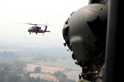 U.S. Army Sgt. Jaime Martinez Jr., a crew chief with 1st Assault Helicopter Battalion, 140th Aviation Regiment, watches his fellow unit members follow him back to refuel, Aug. 23, 2020, in Healdsburg, California. The 1-140th Aviation Regiment is from Los Alamitos, California, and they are assisting the California Department of Forest and Fire Protection (CALFIRE) with the LNU Lightning Complex fire.