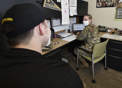 young man talks to female soldier at a desk.