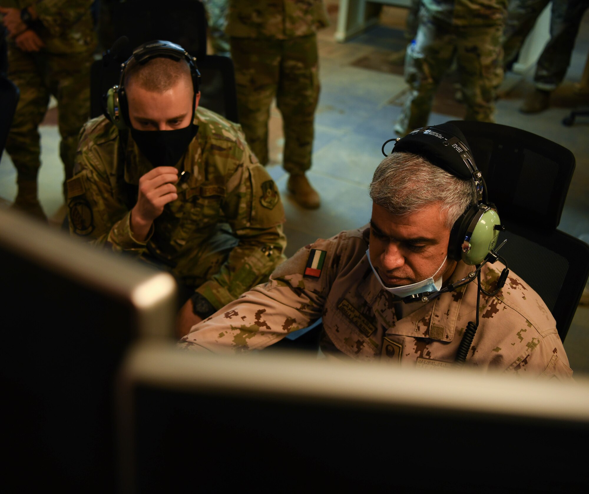 Airman 1st Class Derek Hilton (left), 727th Expeditionary Air Control Squadron weapons director, watches Col. Abdallah Ali Mohamed Al-Bloushi, United Arab Emirates Air Operations Center deputy commander, set up controls during a visit to the 727 EACS headquarters (Kingpin), August 24, 2020, in Al Dhafra Air Base, United Arab Emirates.