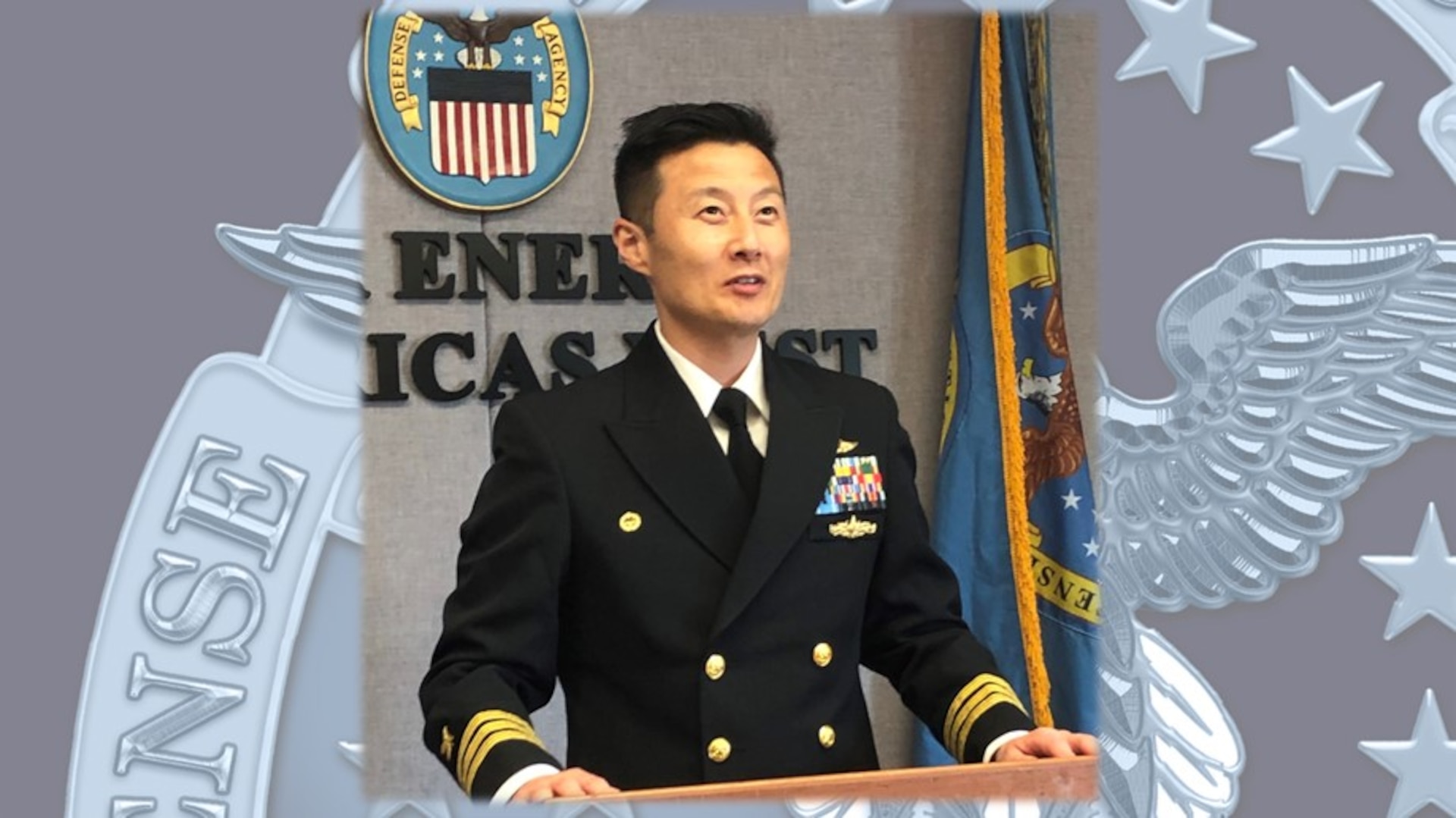 A Navy commander stands at a podium