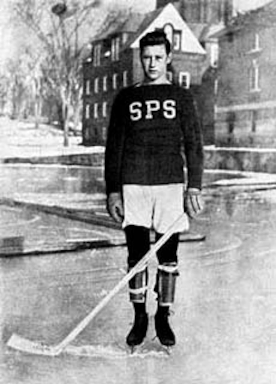 A young man in school hockey gear poses for a photo.