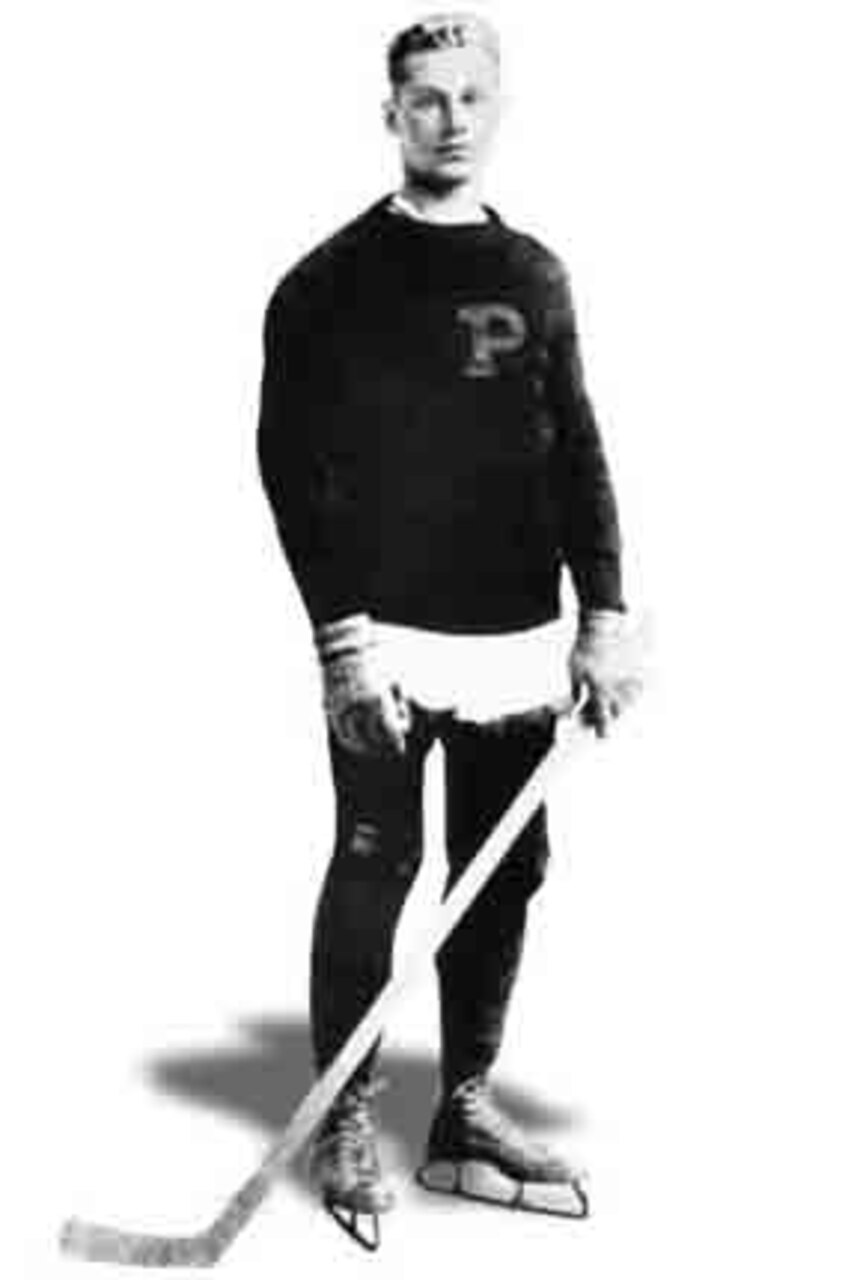 A man in a hockey uniform poses for a photo.