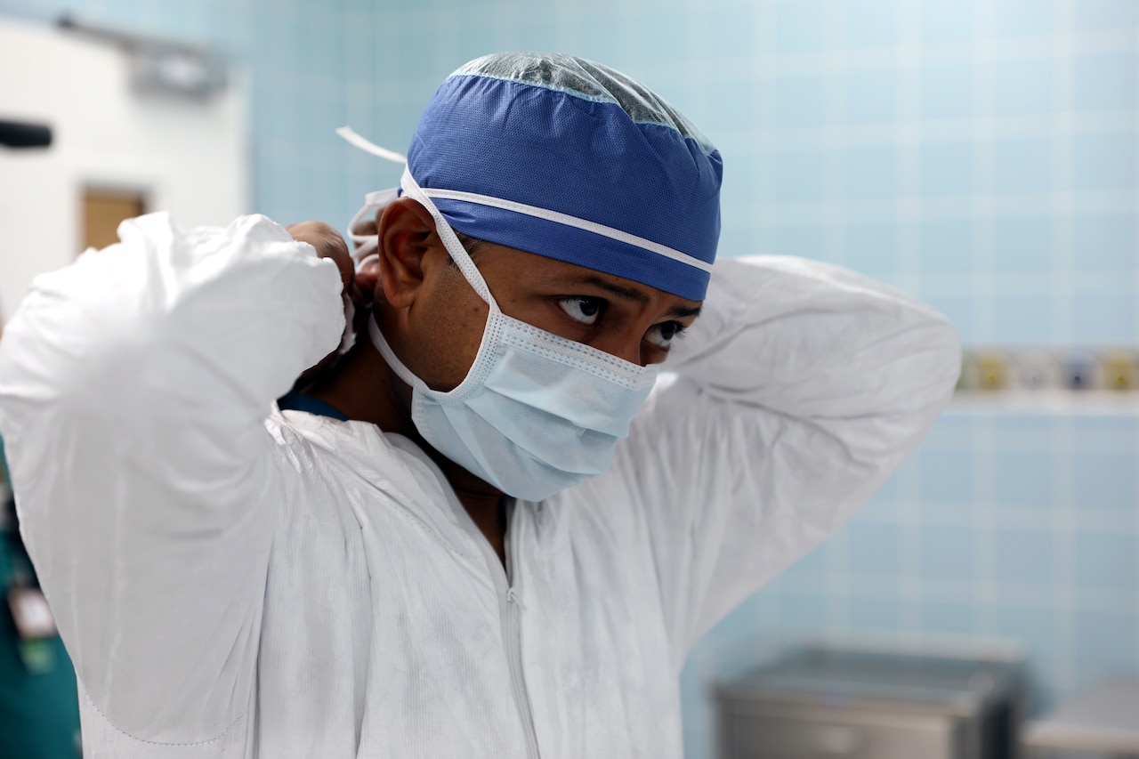 A doctor puts on a face mask in preparation for surgery.