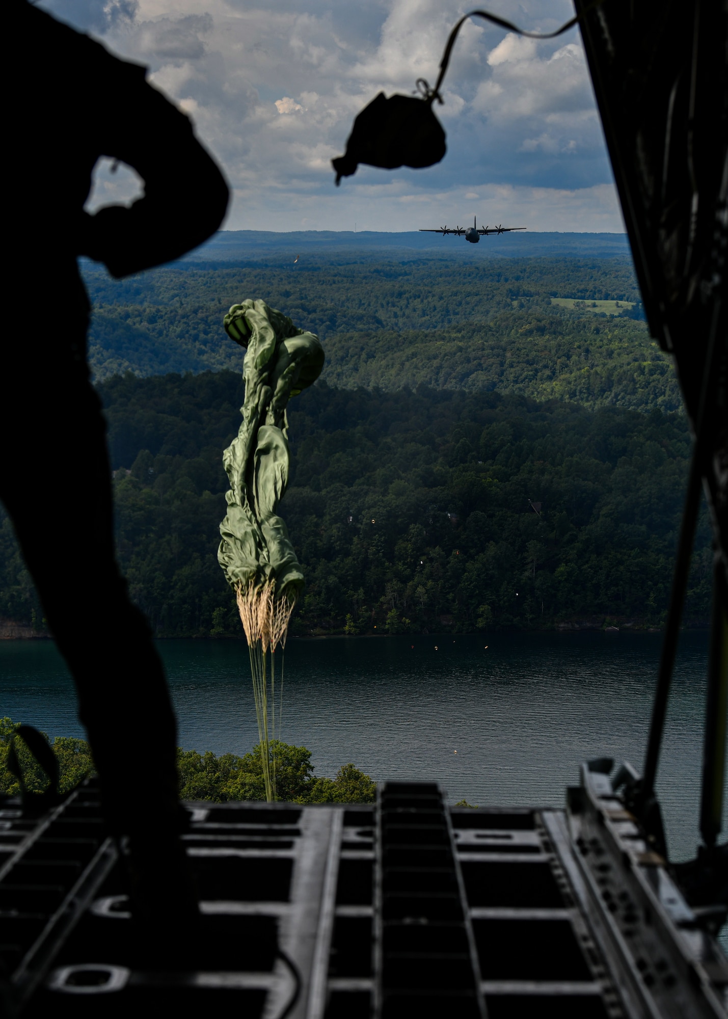 A parachute attached to cargo opens after being pushed out the back of a C-130H Hercules aircraft by a loadmaster on Aug. 23, 2020,  over Summerville Lake, West Virginia. Five Air Force Reserve units from the 22nd Air Force and a West Virginia Air National Guard unit participated in Rally in the Valley, a multi-day C-130 training exercise under a distributed operations concept, Aug. 22-25, 2020. The exercise included cargo drops, high-altitude paratrooper drops, task force resupply and personnel extraction.