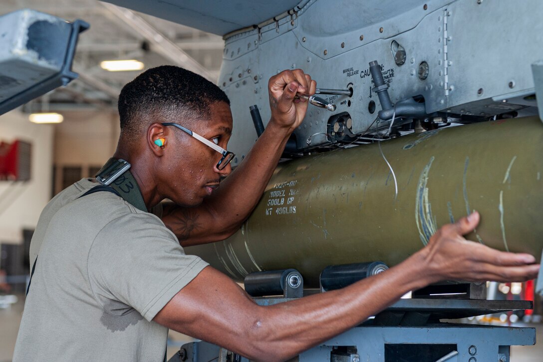 Photo of an Airman securing a munition onto an A-10C Thunderbolt II