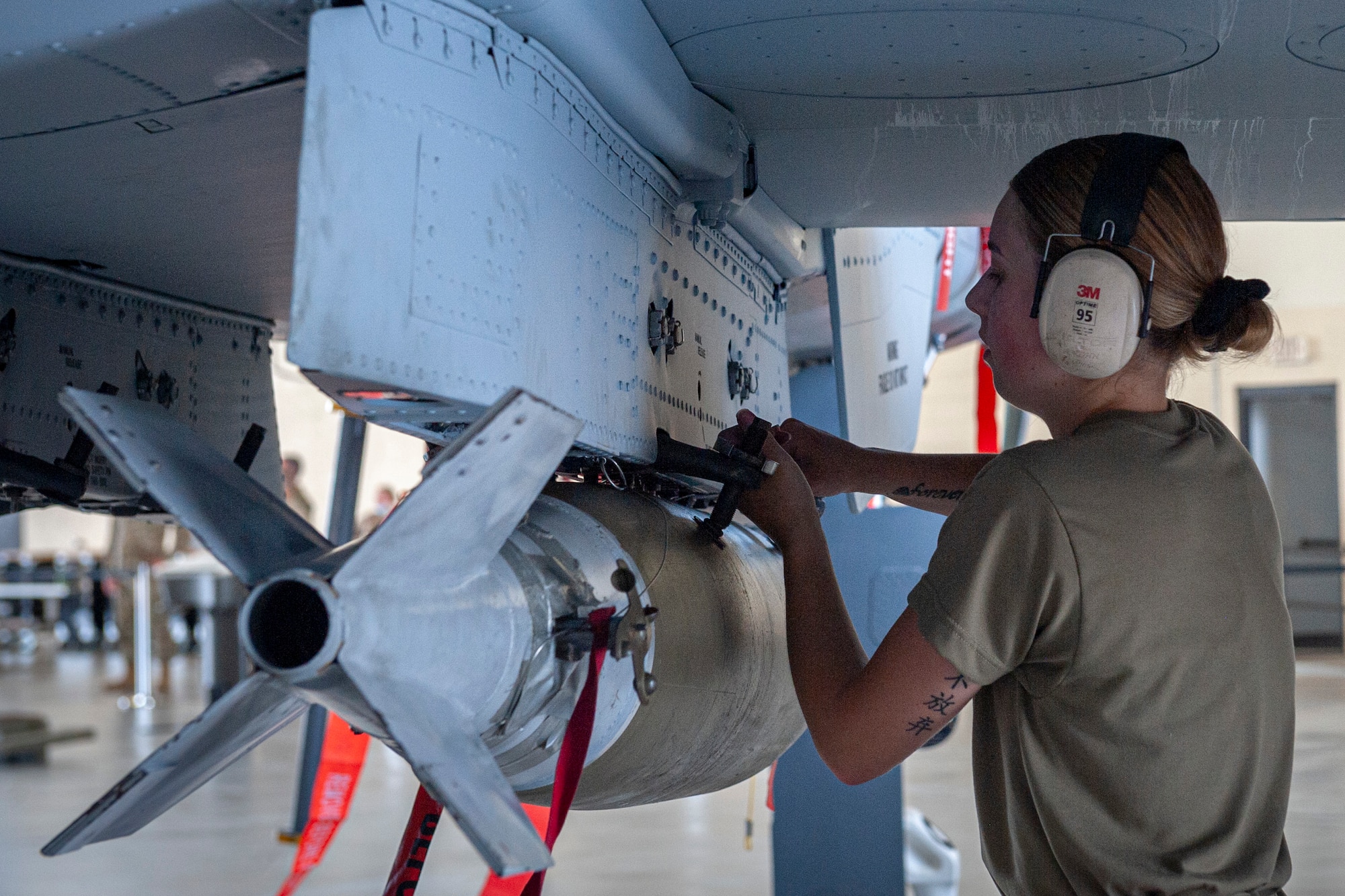 Photo of an Airman securing a munition to an A-10C Thunderbolt II