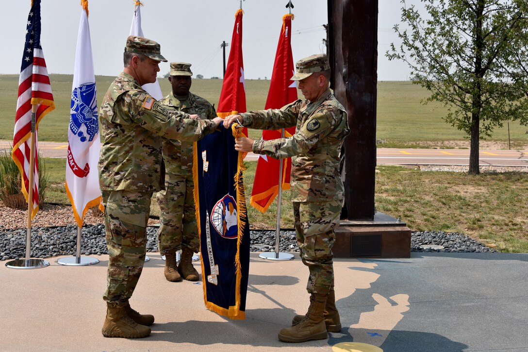 Gen. James H. Dickinson, U.S. Space Command commander, left, and Lt. Gen. Daniel L. Karbler, U.S. Army Space and Missile Defense Command commanding general, unfurl SMDC's colors to officially recognize the command as the Army Service Component Command to USSPACECOM during an. Aug. 21 ceremony at Schriever Air Force Base, Colorado.