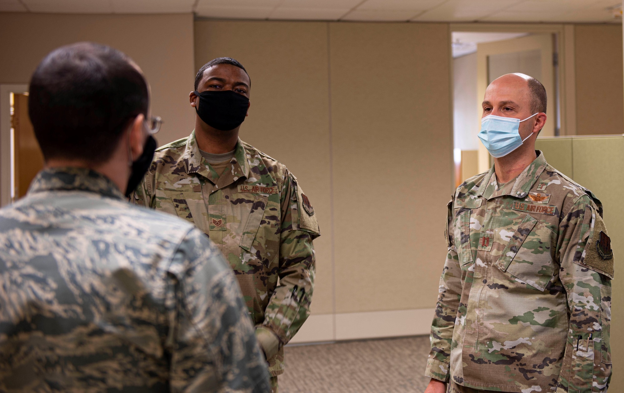 Three Airmen talk in a circle together.