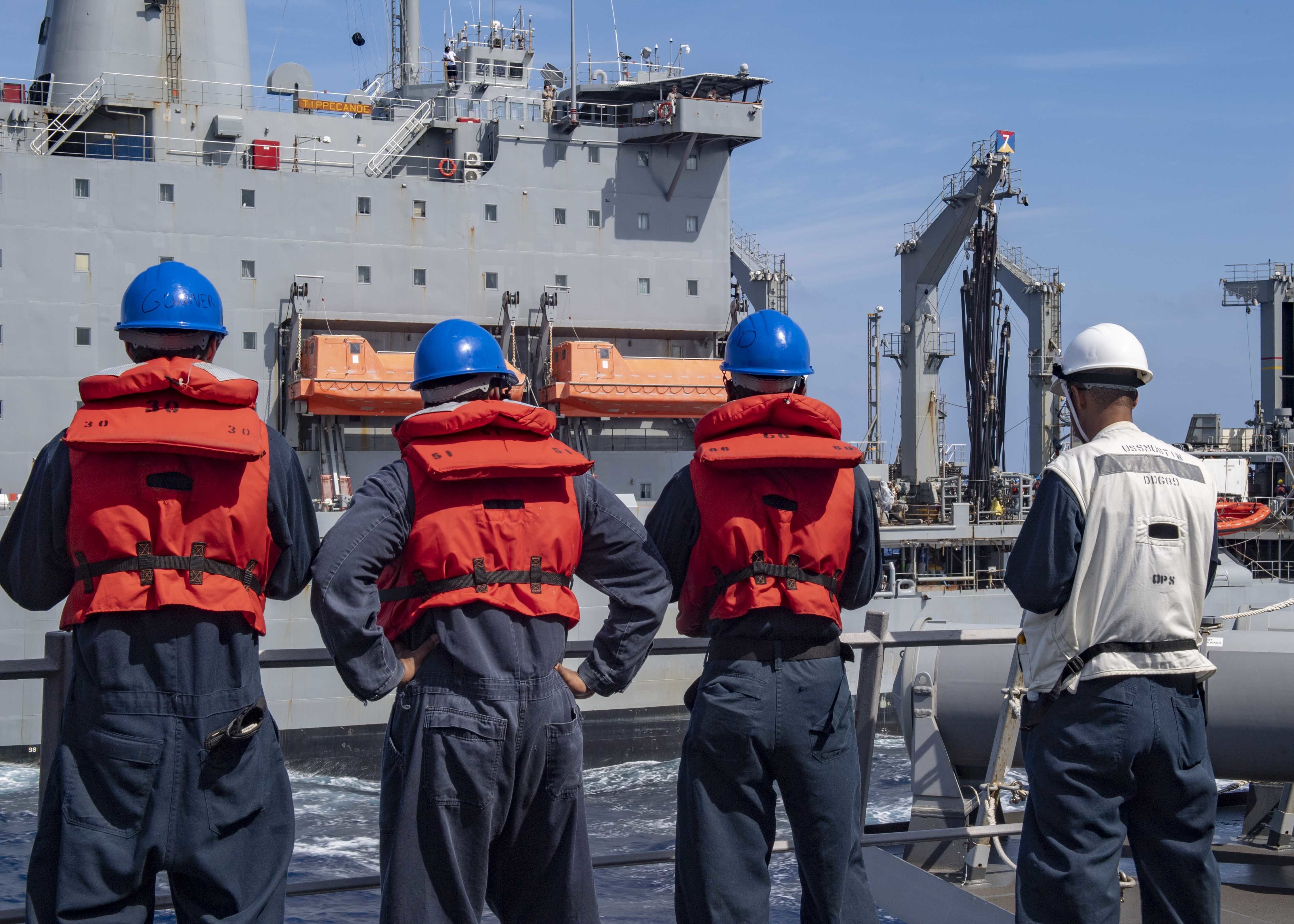 ailors attached to the Arleigh Burke-class guided-missile destroyer USS Mustin (DDG 89) man the rails as Mustin approaches the fleet replenishment oiler USNS Tippecanoe (T-AO 199).