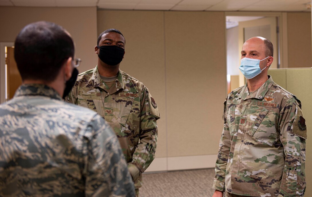 Three Airmen talk in a circle together.