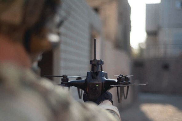 A hand holds a quadcopter drone.