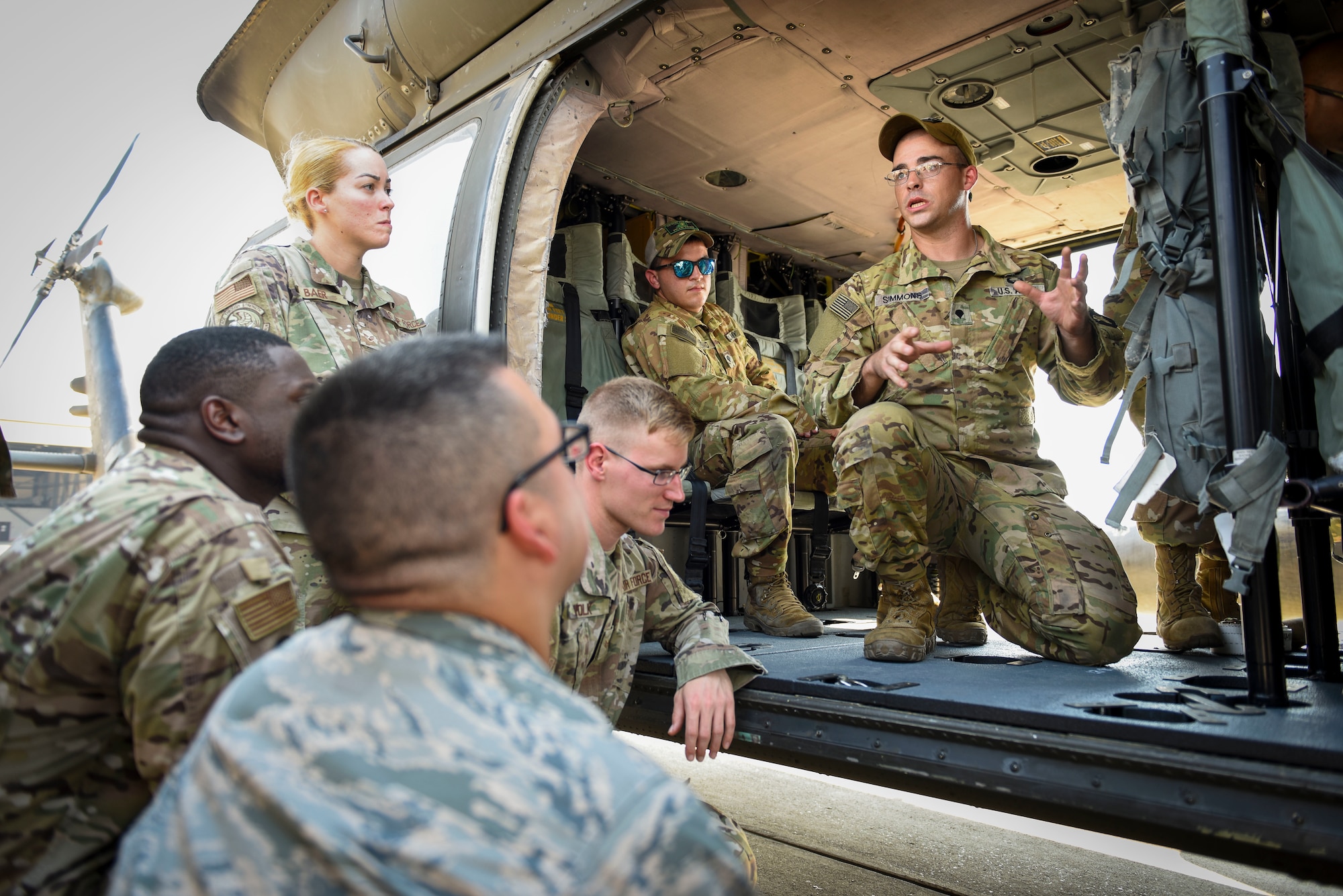 A group of military members listening to another talk inside a helicopter
