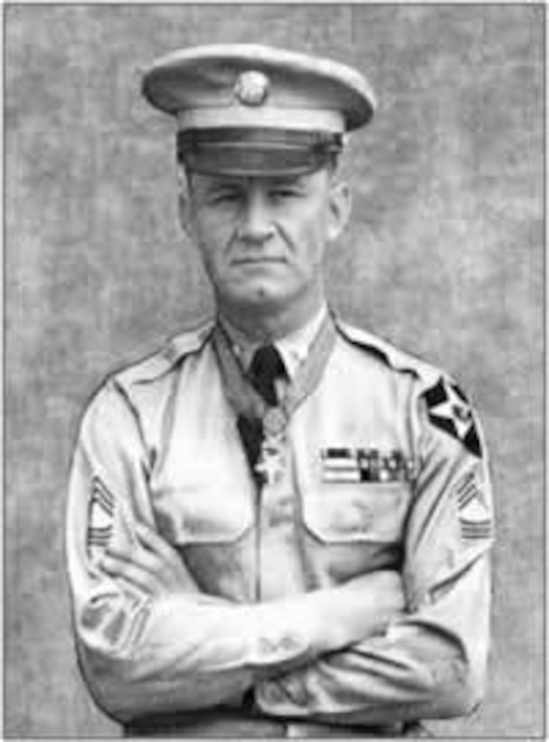 A man in uniform and with the Medal of Honor hanging from a ribbon around his neck stands with his arms crossed.