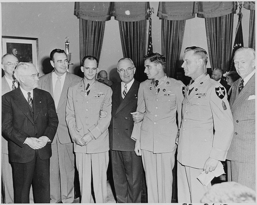 Eight men, including three soldiers, stand together for a photo.