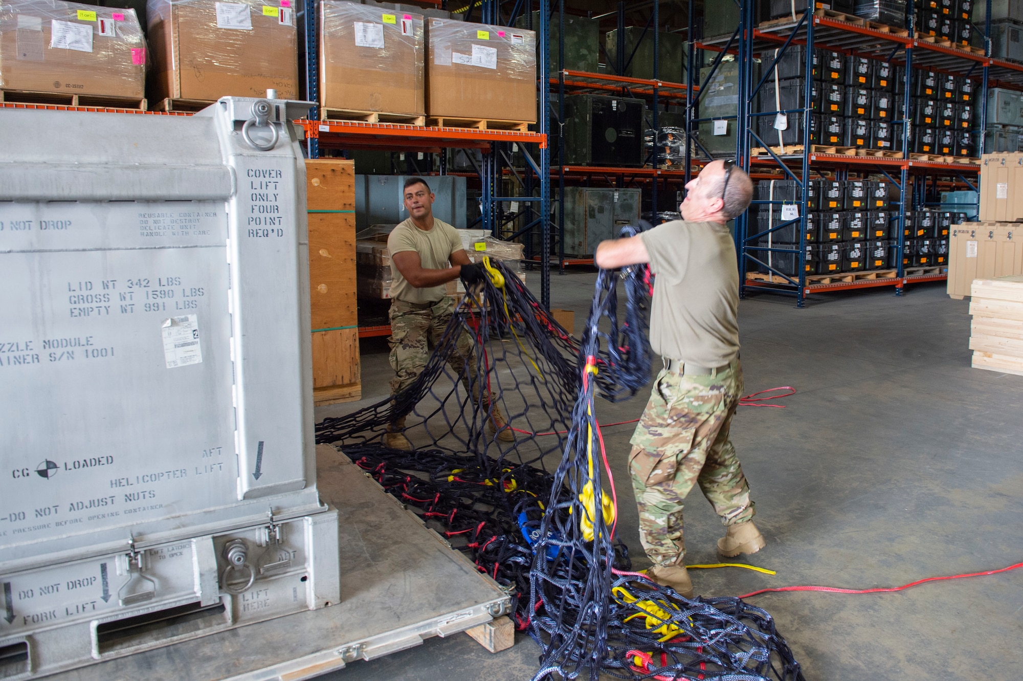 Airman 1st Class Dalton White and Senior Airman Ed Aromi, both 49th Aerial Port Squadron cargo representatives, throw a net over cargo at Grissom Air Reserve Base, Indiana Aug. 26, 2020. During the visit, the 49th APS learned differences in ways the Royal Air Force store cargo. (U.S. Air Force photo/Senior Airman Michael Hunsaker)