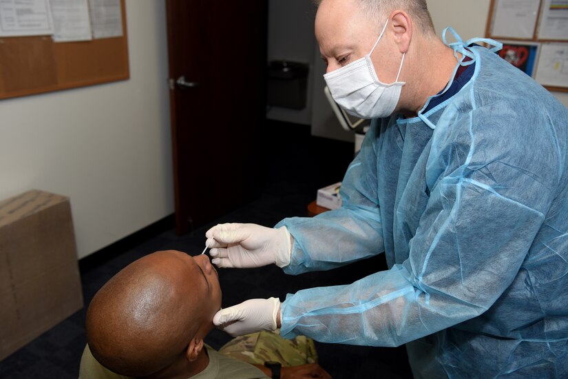 An airman wearing a face mask tests another airman for COVID-19.