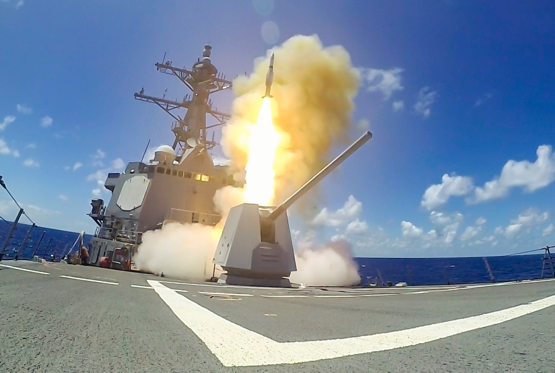 A missile launches from a ship in the ocean.