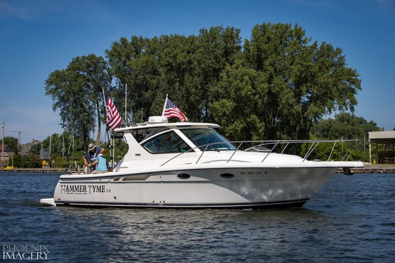 Three men on a boat with two American flags.