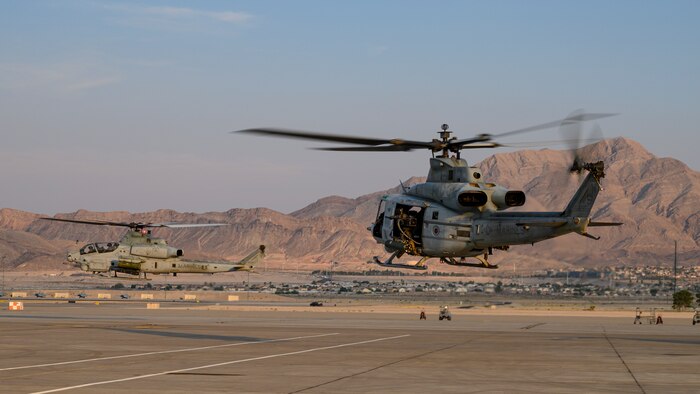 Helicopters take off from the flight line.