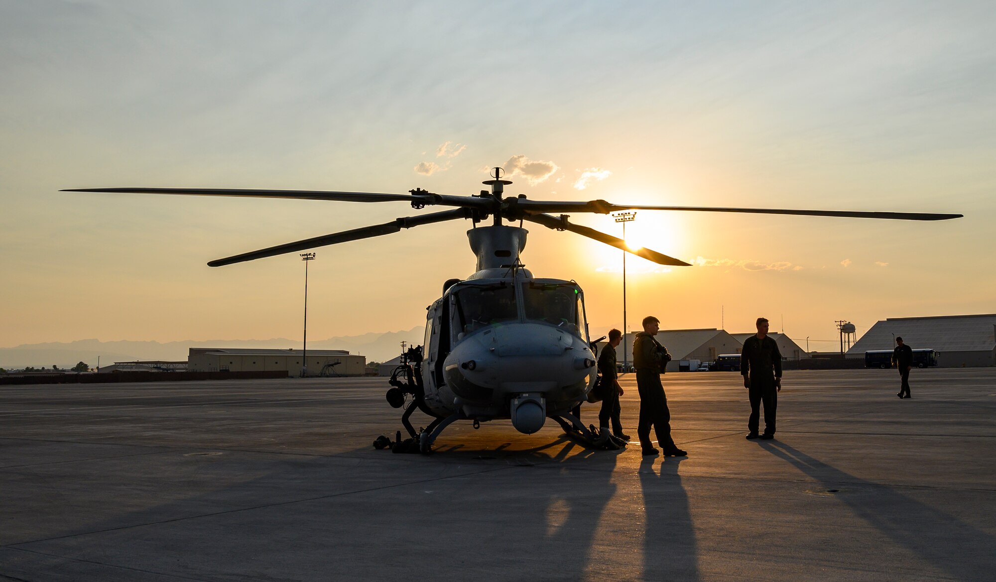 Marines stand next to helicopter on flight line.