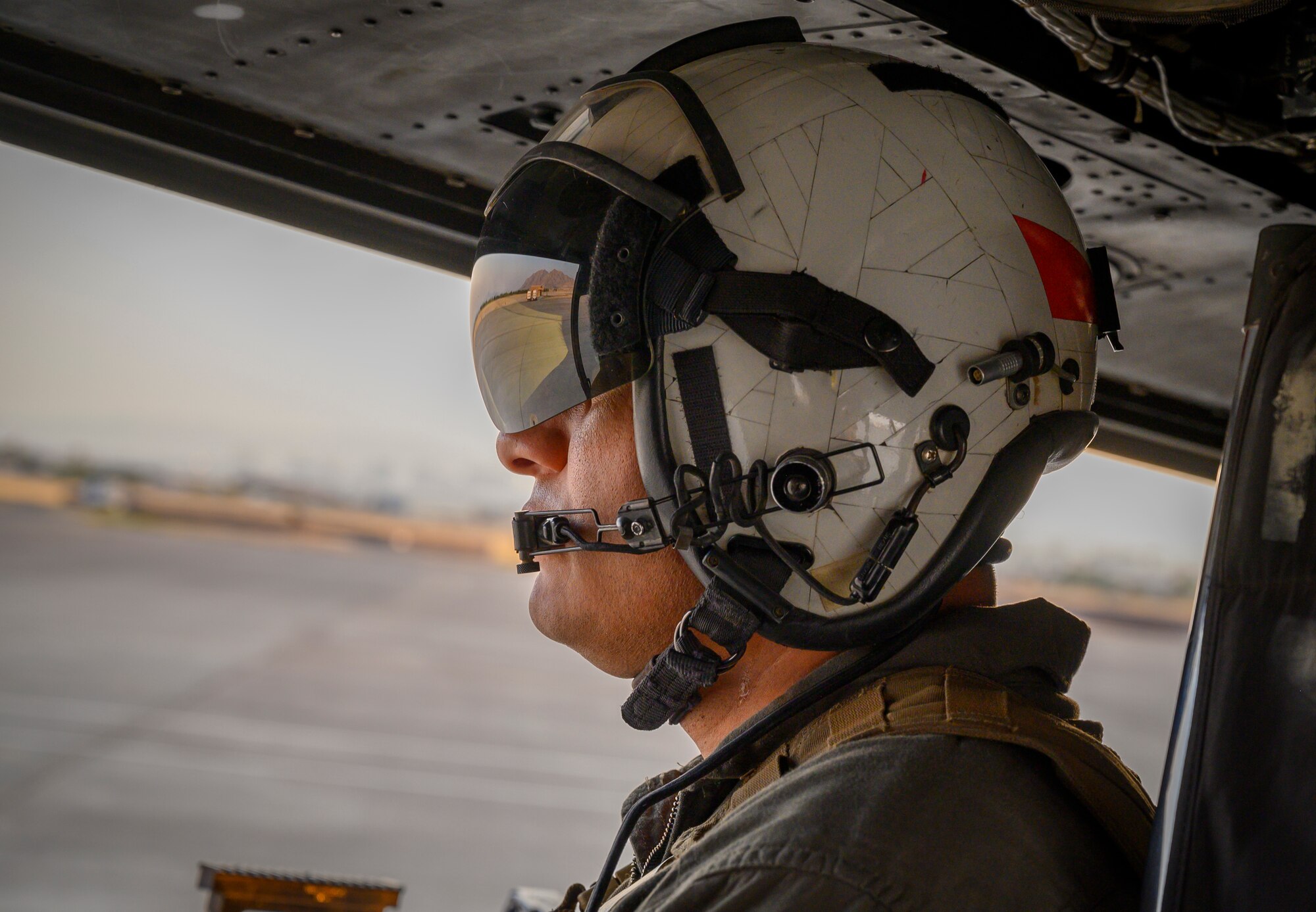 Marine looks out of helicopter on flight line.
