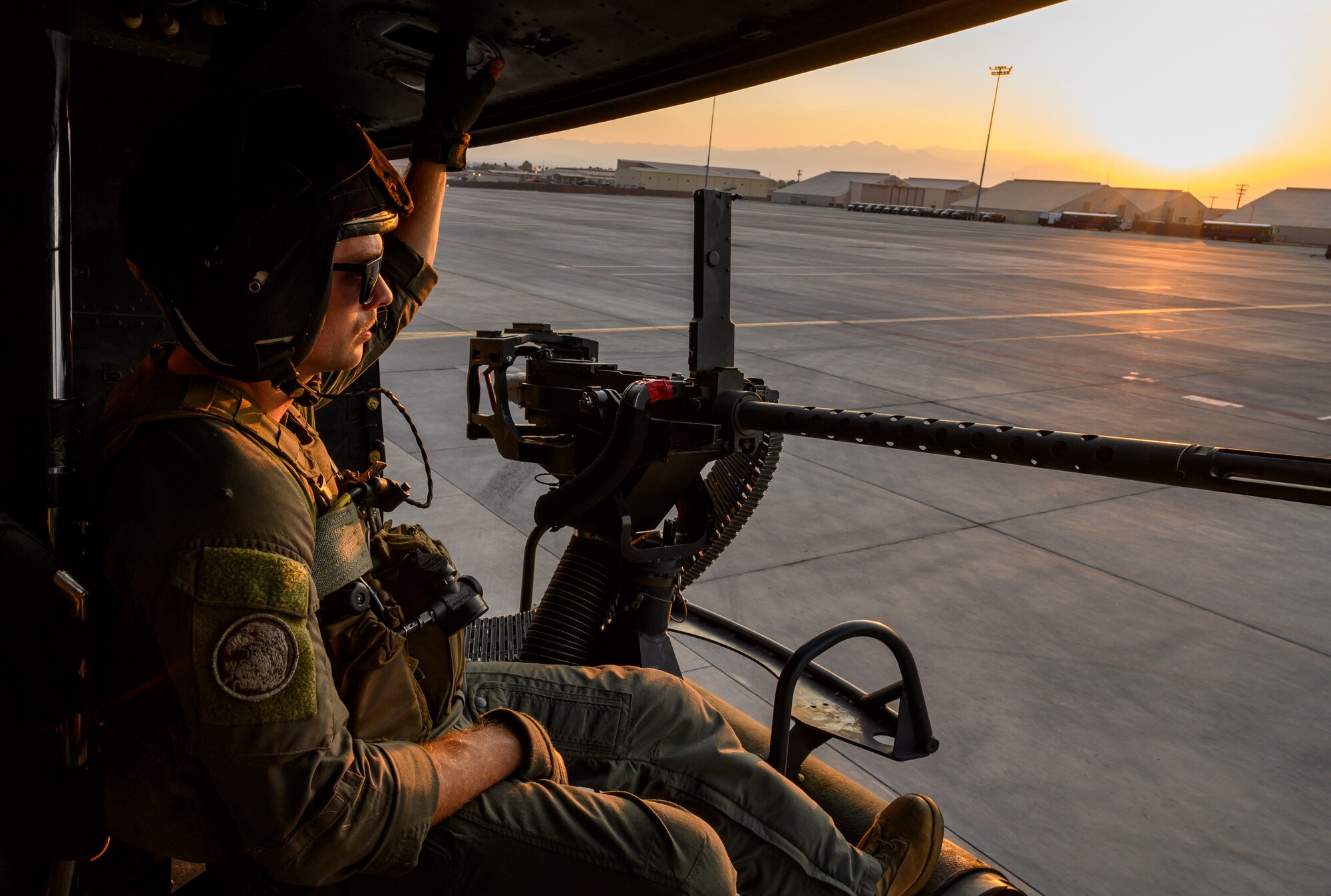 Marine sits in helicopter on flight line.