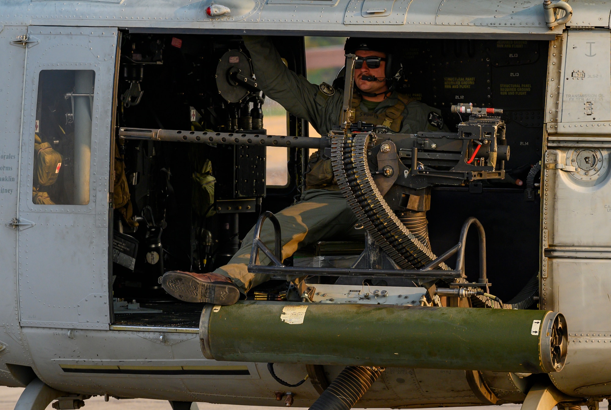 Marine sits in helicopter on flight line.