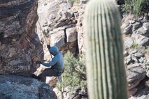 A photo of an Airman rappelling down a rock