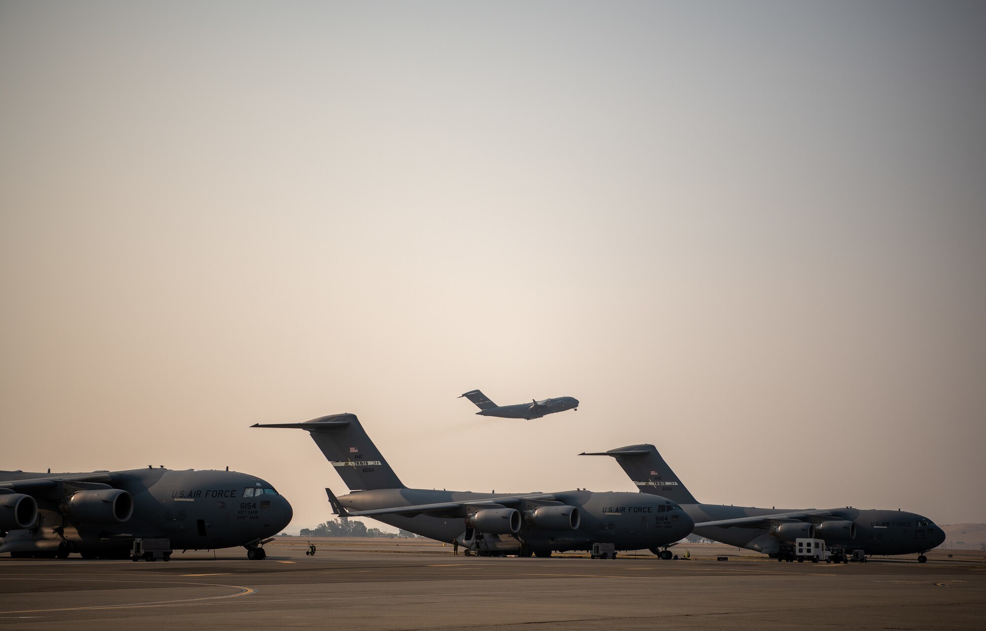 A C-17 takes off behind a row of other C-17s.