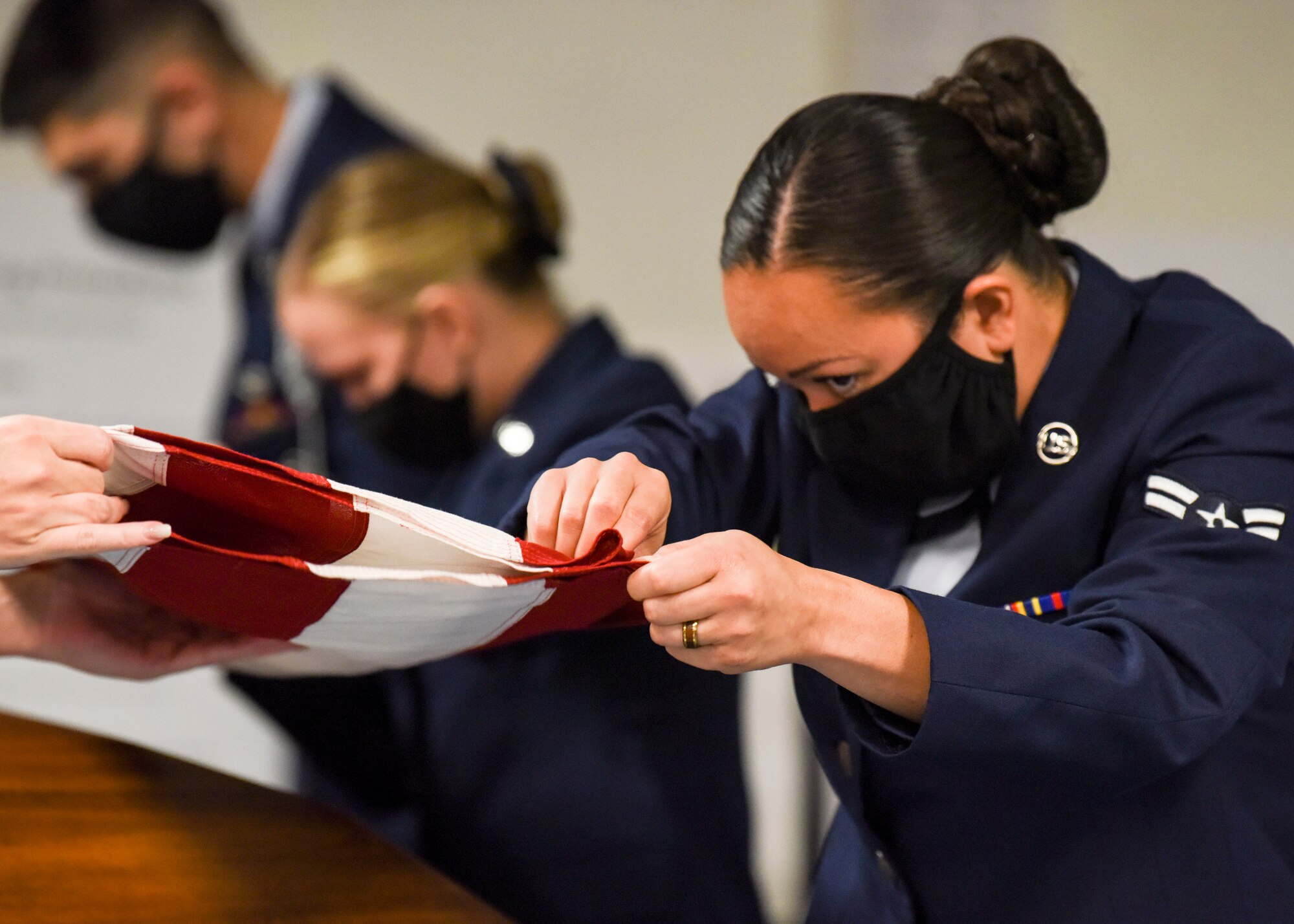 U.S. Air Force Staff Sgt. Kara Tierney and Airman 1st Class Fuatapu Hook ceremonial guardsmen with the Joint Base Elmendorf-Richardson Honor Guard, fold a U.S. flag during a six-man funeral sequence during an Honor Guard graduation ceremony at Joint Base Elmendorf-Richardson, Alaska, Aug. 26, 2020. The primary mission of the base Honor Guard program is to employ, equip and train Air Force members to provide professional military funeral honors for active duty members, retirees and veterans. In January of 2000, public law was implemented, providing all veterans the right to a funeral ceremony that includes, at minimum, the folding of a U.S. flag, presentation of the flag to the veteran’s family and the playing of “Taps.” (U.S. Air Force photo by Senior Airman Crystal A. Jenkins)