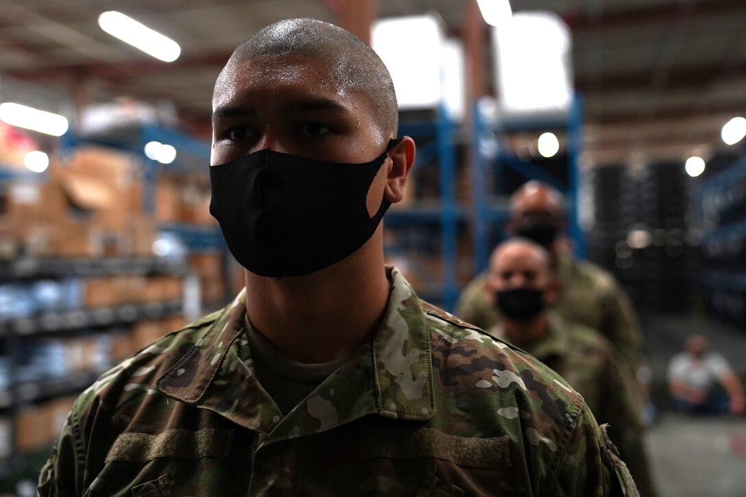 Basic military training trainees from the 737th Training Wing Detachment 5 wait in line to get their issued military clothing inspected inside the 81st Logistics Readiness Squadron warehouse at Keesler Air Force Base, Mississippi, Aug. 26, 2020. The 81st LRS worked with different Air Education and Training Command units to support BMT at Keesler by providing uniforms for trainees. (U.S. Air Force photo by Airman 1st Class Seth Haddix)