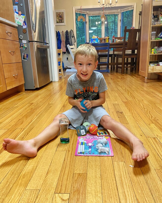 Abraham Lemery, a U.S. Air Force family member, holds toys from a sensory box in his home outside Amherst, Mass., earlier this month. The Hanscom Exceptional Family Member Program sent the boxes to enrolled families to supplement therapy for children on the Autism Spectrum or with sensory processing needs. (Photo courtesy of Lt. Col. Dave Lemery)
