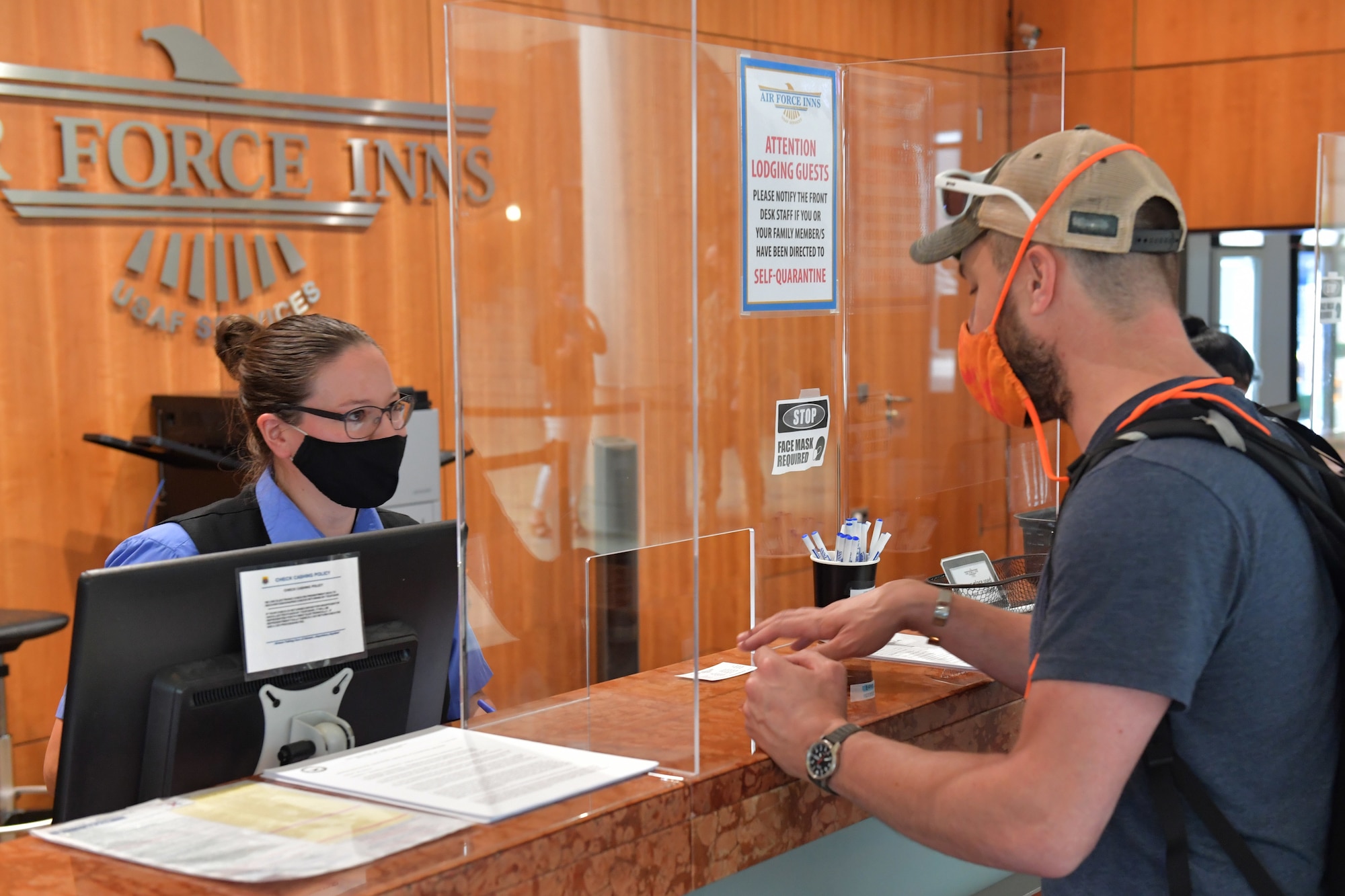 A hotel worker helping a customer at the front desk.