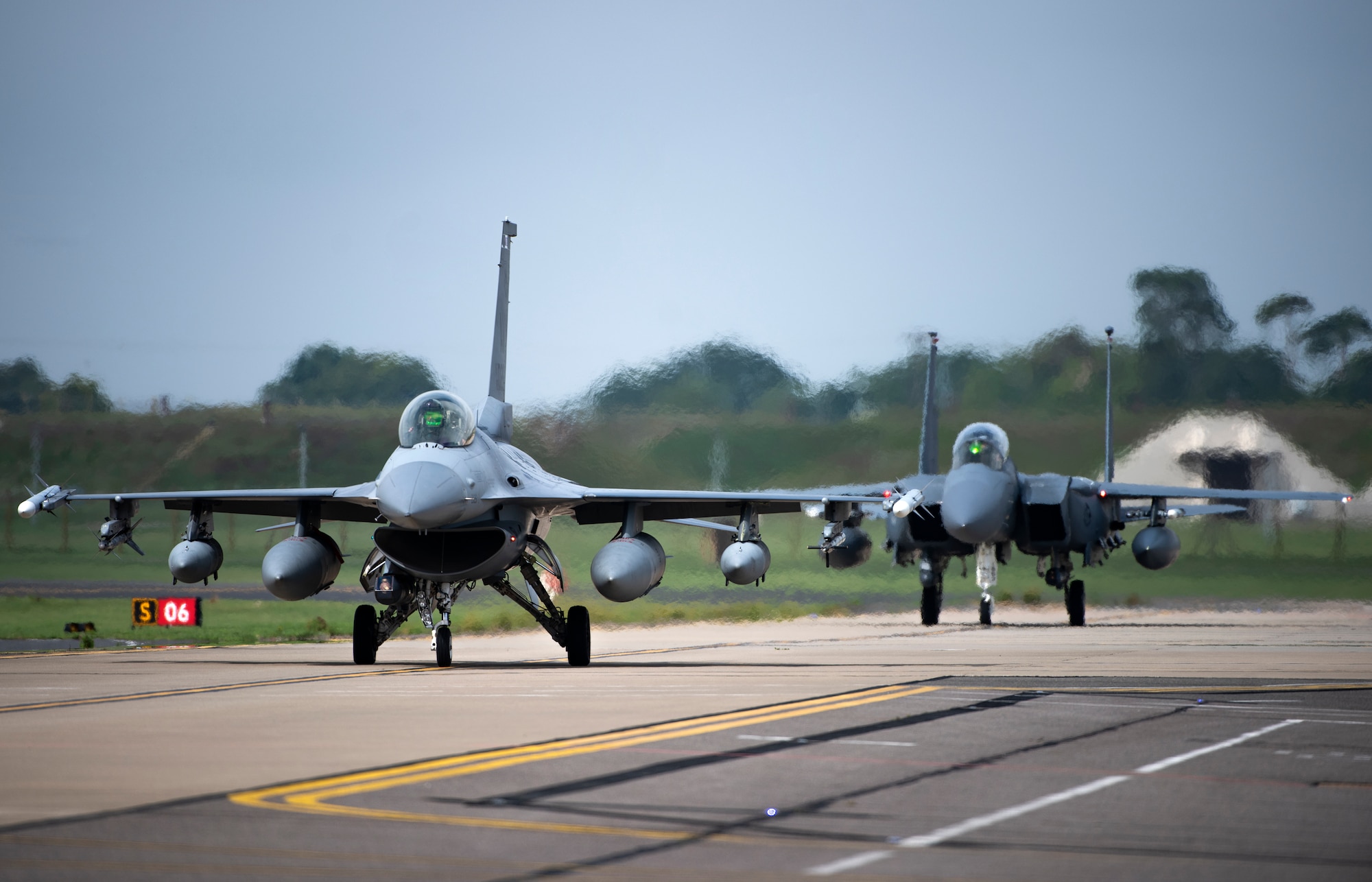 A U.S. Air Force F-16 Fighting Falcon, assigned to the 510th Fighter Squadron, Aviano Air Base, Italy, and an F-15E Strike Eagle, assigned to the 494th Fighter Squadron, taxi down the flightline at Royal Air Force Lakenheath, England, Aug. 28, 2020. Aircraft and Airmen from the 510th FS are participating in a flying training deployment event to enhance interoperability, maintain joint readiness and strengthen relationships with regional allies and partners. (U.S. Air Force photo by Airman 1st Class Jessi Monte)