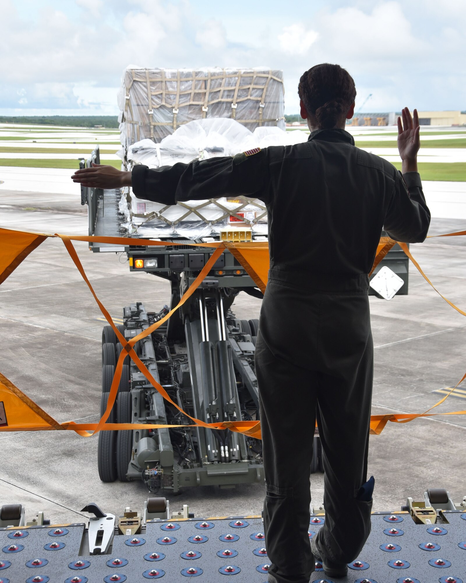 Senior Airman Madison Doherty, 924th Air Refueling Squadron boom operator and load master, directs an a military aircraft cargo loader, before it offloads a pallet onto a KC-46A Pegasus assigned to the 22nd Air Refueling Wing, Aug. 20, 2020, Andersen Air Base, Guam. Doherty was part of the first 931st Air Refueling Wing-lead KC-46 cargo load mission that stopped at four locations in six days.