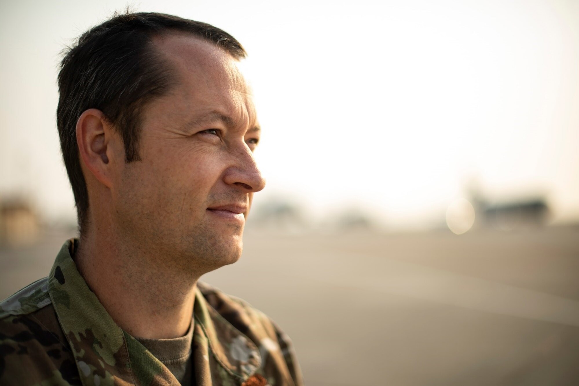A man in a military uniform looks out at a flight line