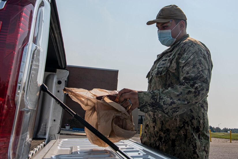 A sailor puts groceries in a truck.