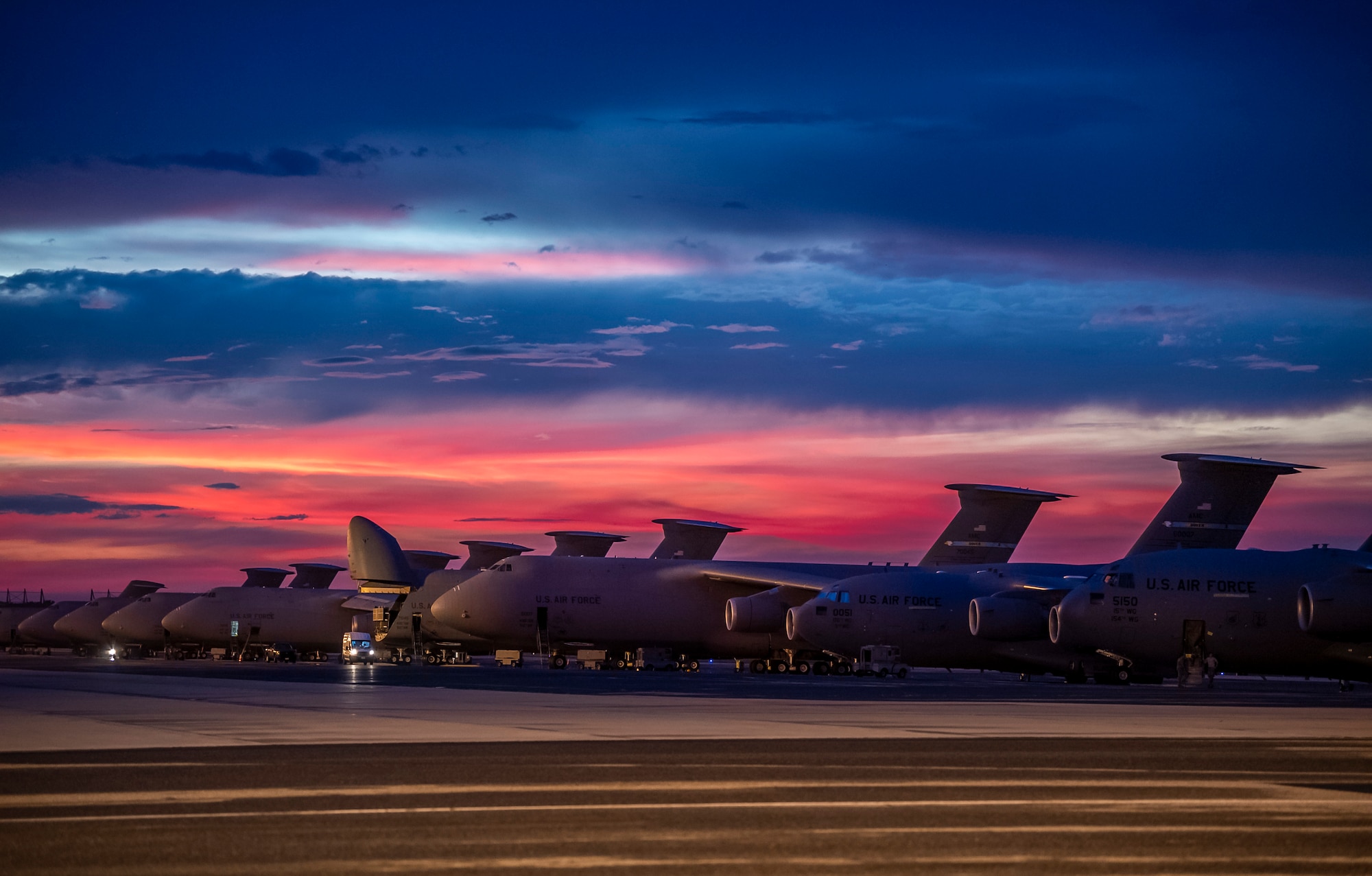The sun sets over Dover Air Force Base, Delaware, as Airmen work on the flight line Aug. 12, 2020.  The 436th Airlift Wing generates global strategic airlift with both C-5M Super Galaxy and C-17A Globemaster III.  (U.S. Air Force photo by Senior Airman Christopher Quail)