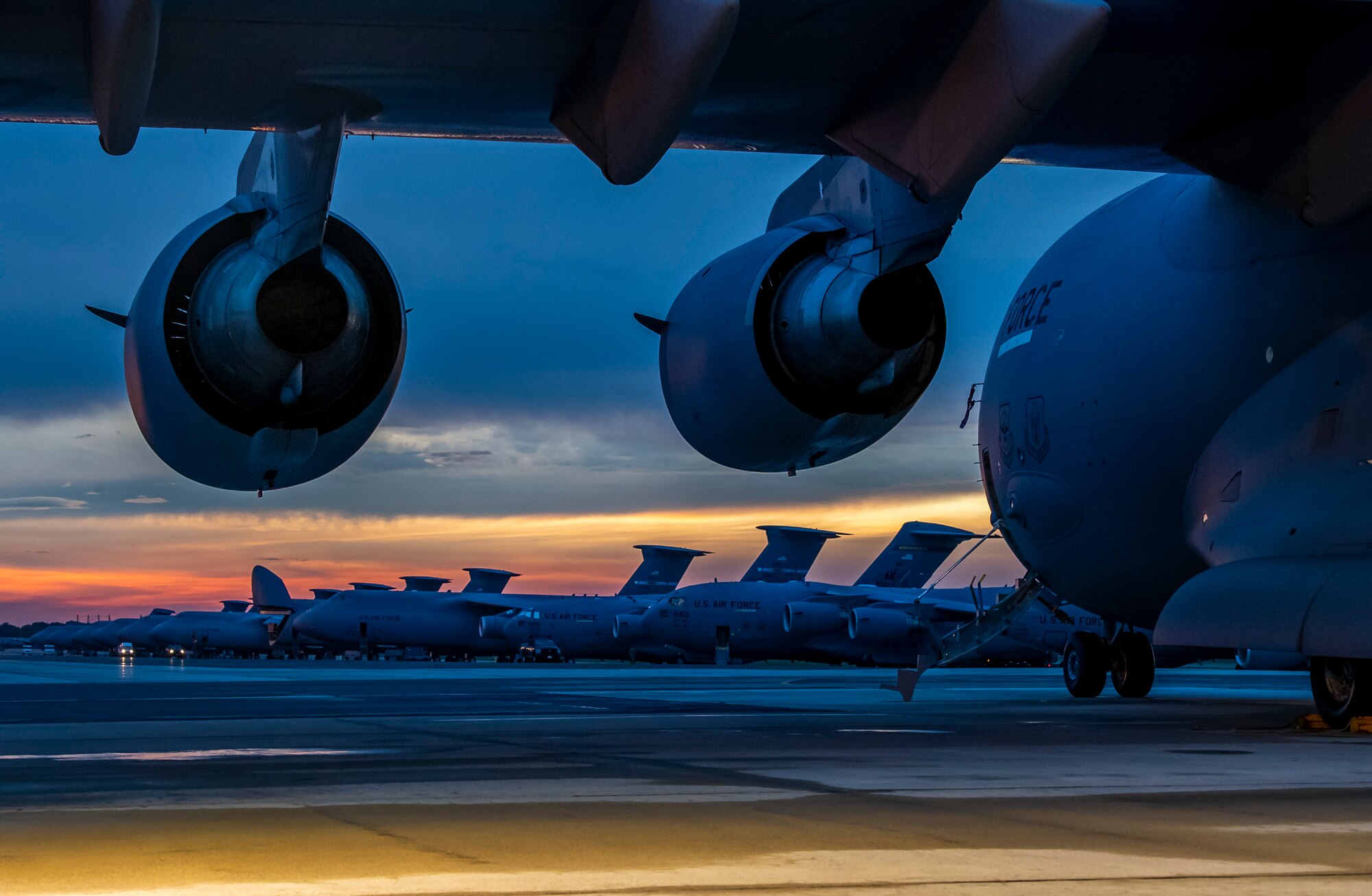 The sun sets over Dover Air Force Base, Delaware, as Airmen work on the flight line Aug. 12, 2020.  The 436th Airlift Wing generates global strategic airlift with both C-5M Super Galaxy and C-17A Globemaster III.  (U.S. Air Force photo by Senior Airman Christopher Quail)