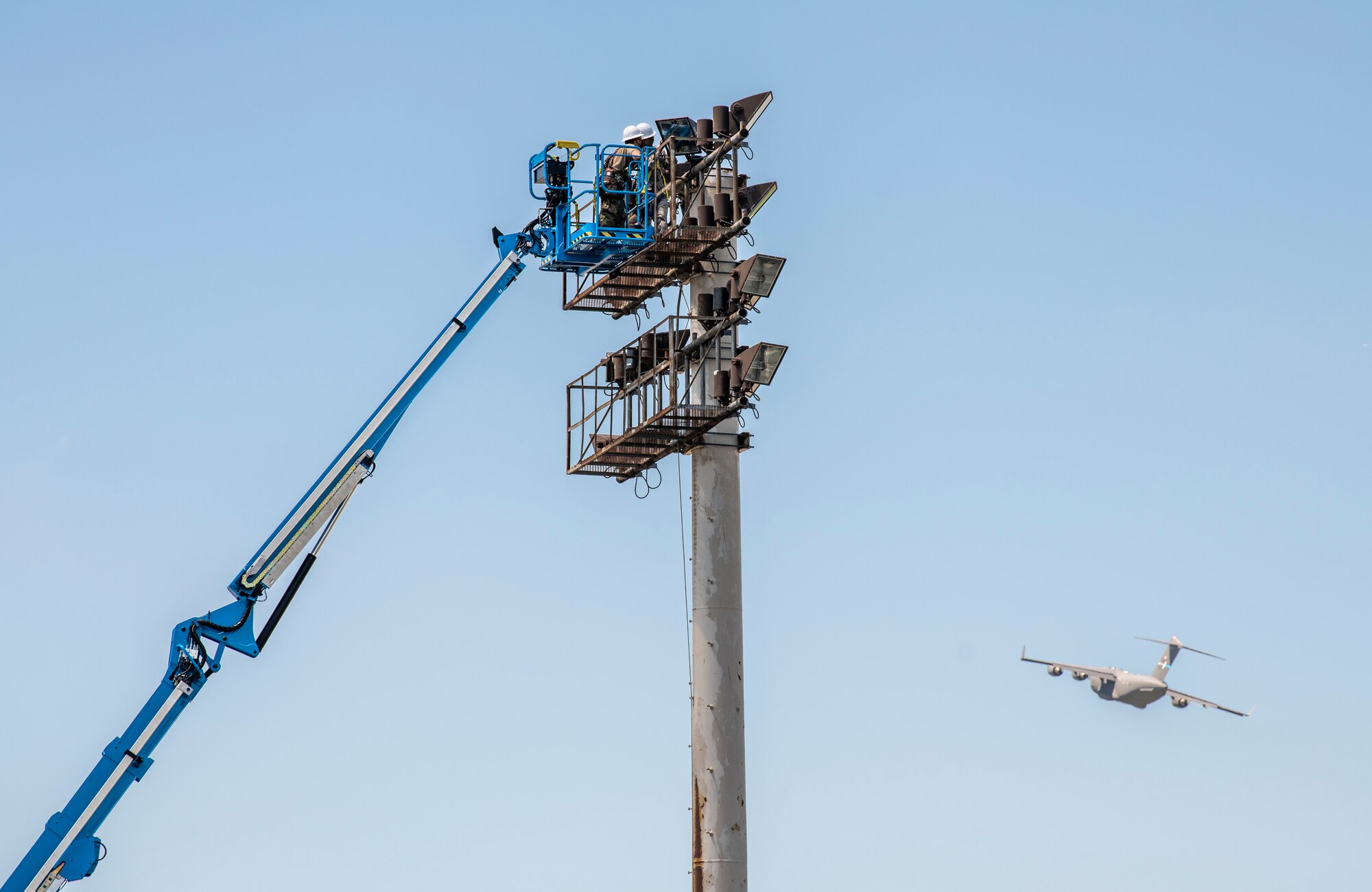 436th Civil Engineer Squadron Airmen repair the lights on the flight line at Dover Air Force Base, Delaware, July 29, 2020 as a 3rd Airlift Squadron, C-17A Globemaster III takes off. Twenty percent of the nation’s out sized airlift capacity is generated from Dover AFB. U.S. Air Force photo by Senior Airman Christopher Quail)