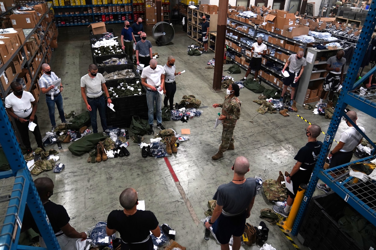An airman hands out uniform items to trainees.