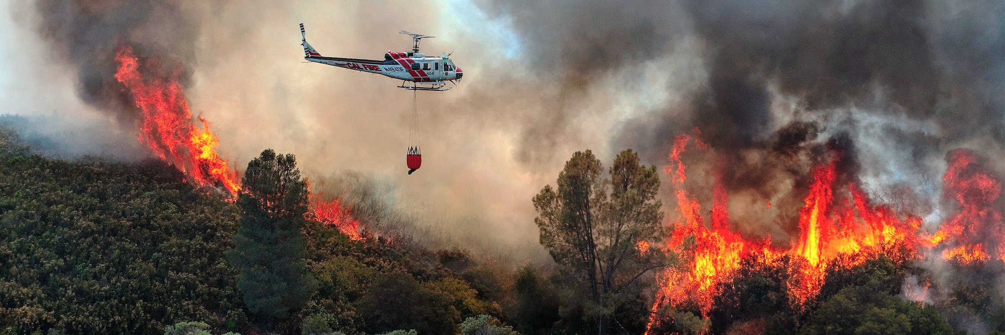 Helicopter flies over wildfire.