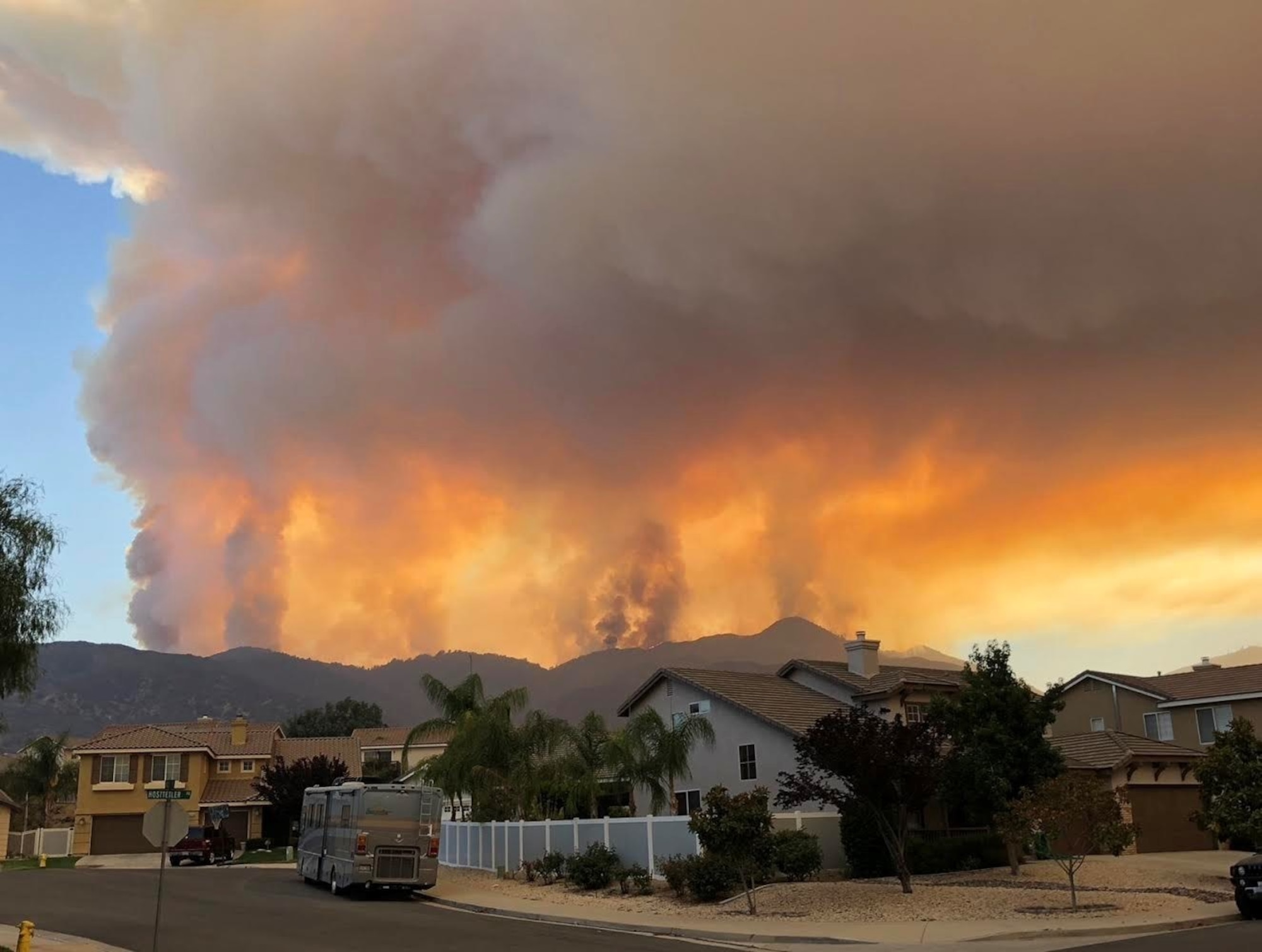 Wildfire rages along skyline behind a residential area.